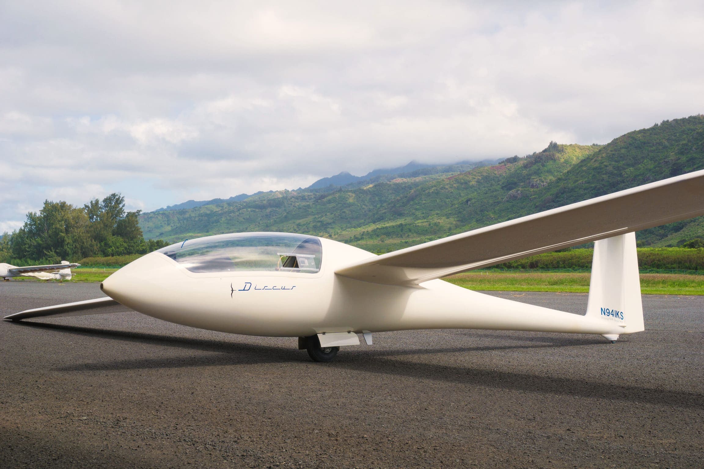 White glider parked on the ramp under a clear sky