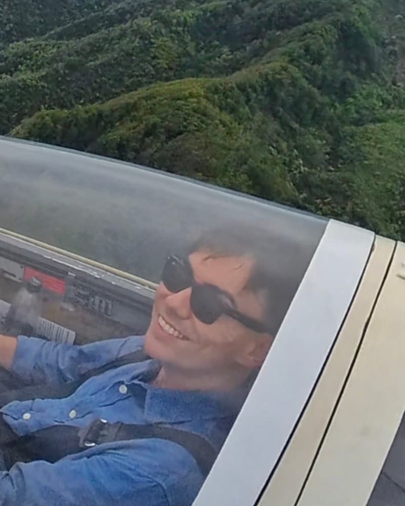 Nathan Van Kempen smiling in a glider cockpit, the Koʻolau mountains behind him