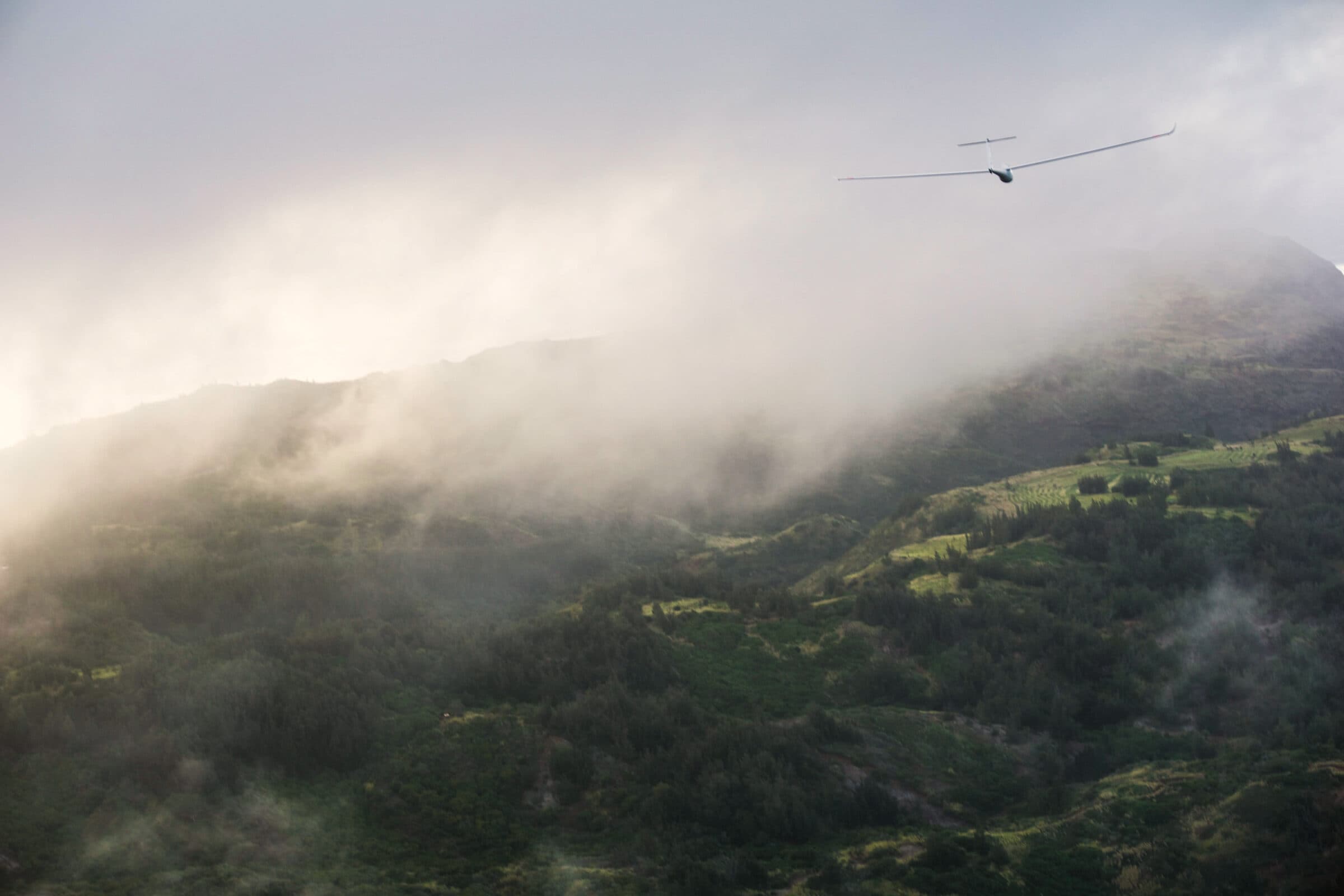 Glider above the misty green mountains behind Oahu's North Shore